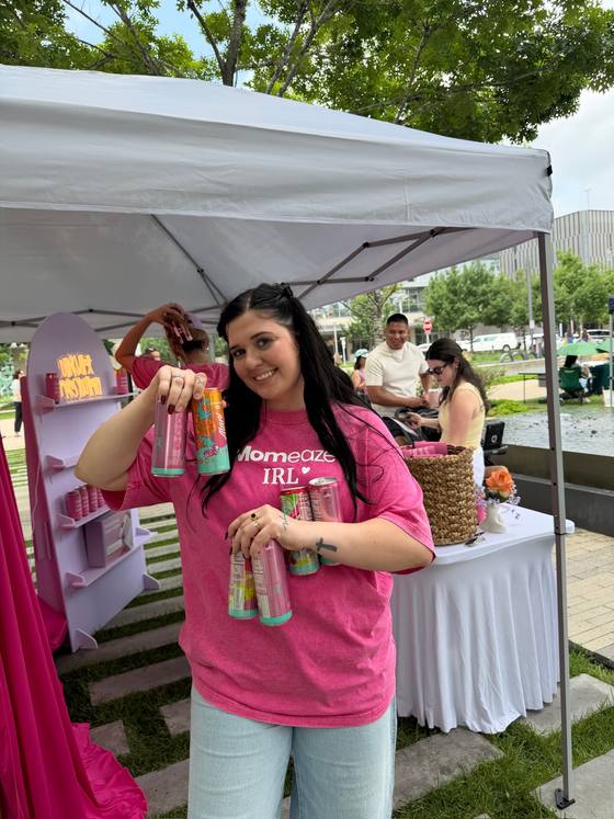 A teammate at the pop-up with both arms full of drinks, handing them out