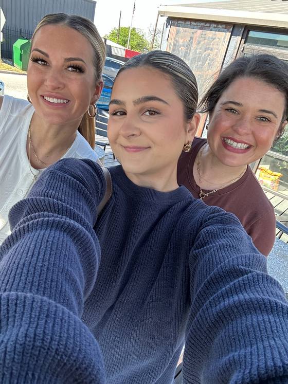 Three of the team leaning into a selfie at a patio table