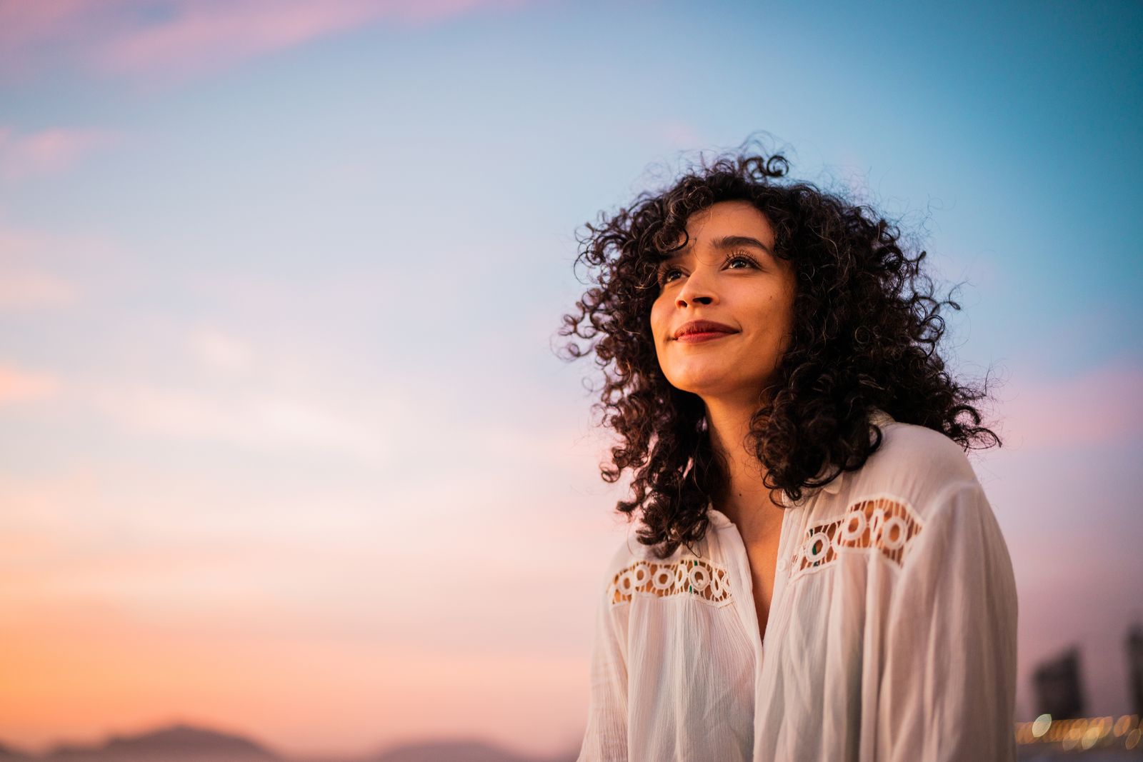 A woman standing outdoors at dusk, looking out at the view
