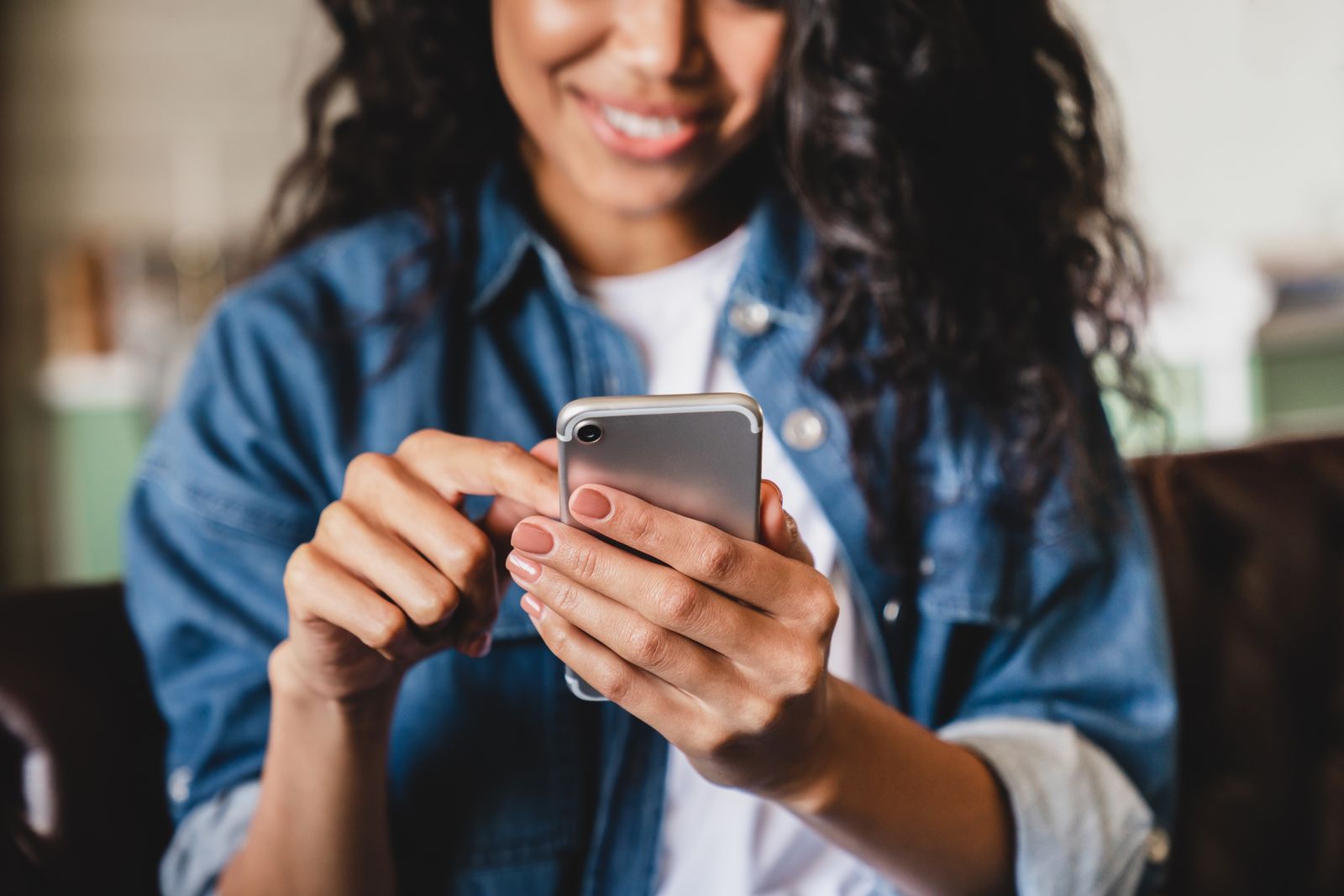 A woman smiling at her phone at home